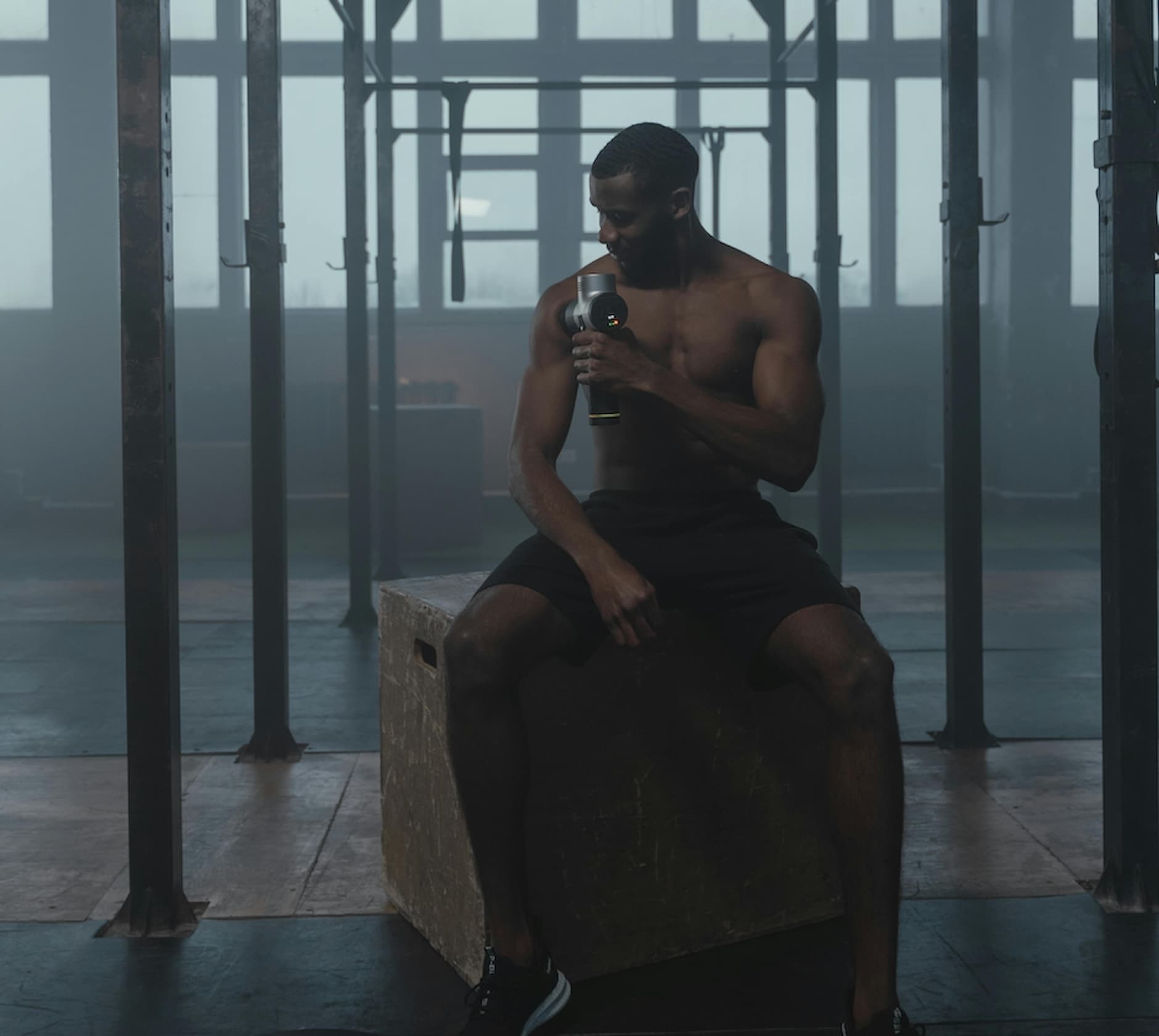 Male athlete using a massage gun for muscle recovery after a workout, promoting physical recovery and better sleep through post-exercise relaxation.
