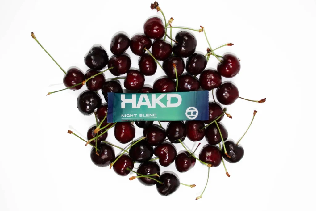 HAKD Night Blend Cherry Chill flavour sachet surrounded by fresh Montmorency cherries, highlighting natural ingredients for better sleep