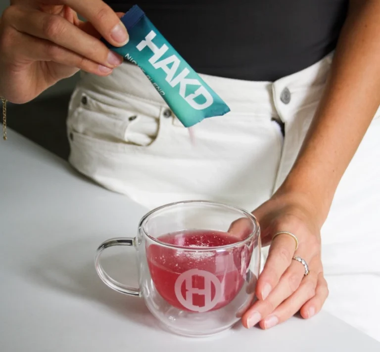 HAKD Night Blend sleep supplement being poured into a mug of water, demonstrating how to use the sachet for better sleep and recovery.