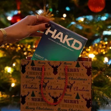 Christmas 2025 Sleep Wishlist featuring HAKD sleep products held in front of a decorated Christmas tree